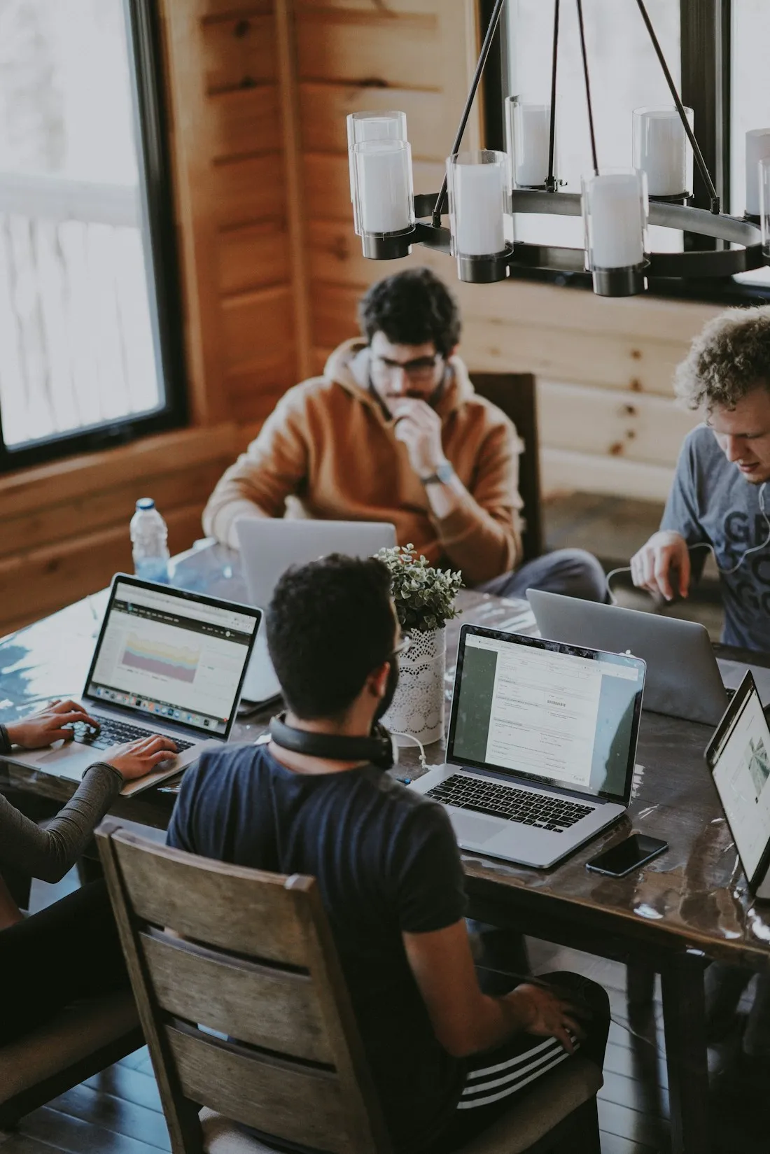 A team working around a table; one person sits back, thinking