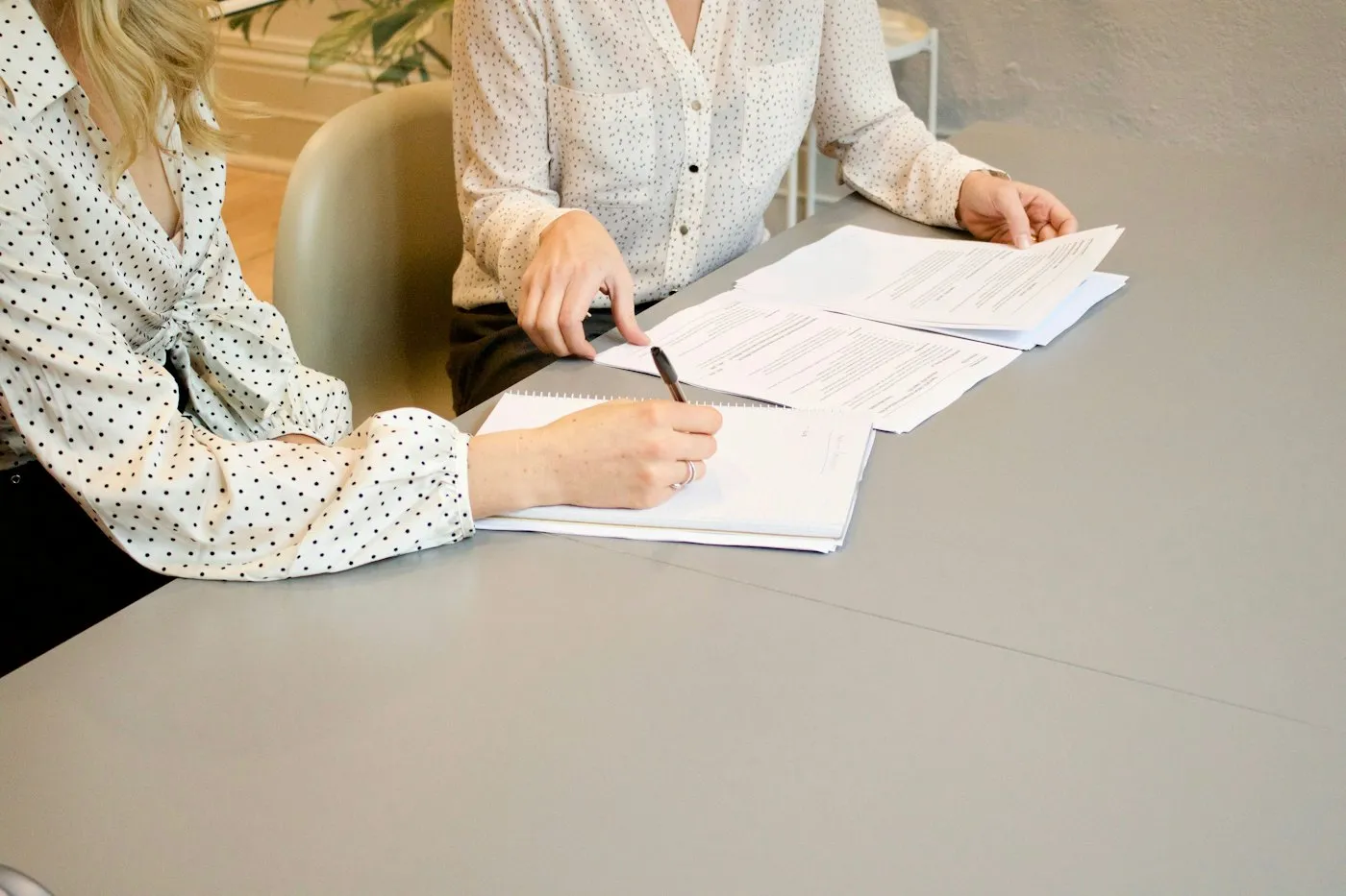 Two colleagues reviewing and signing documents at a table