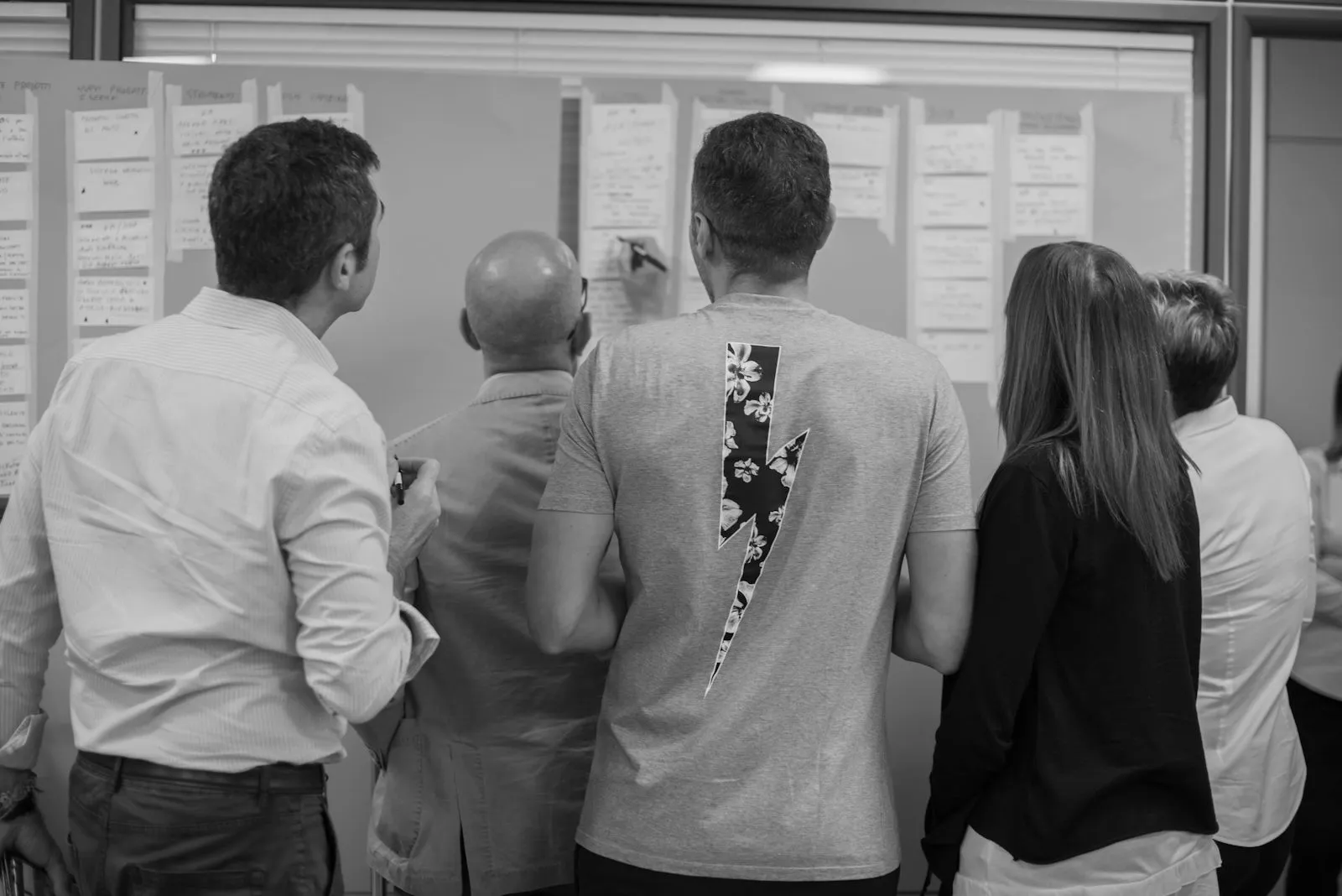 A team standing at a wall of sticky notes, mapping their work together